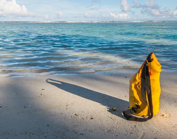 Segelbeutel steht am Meer im Sand