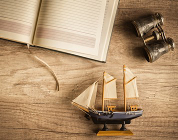 Logbuch zum Segeln Leeres Logbuch und Modellboot auf Holztisch