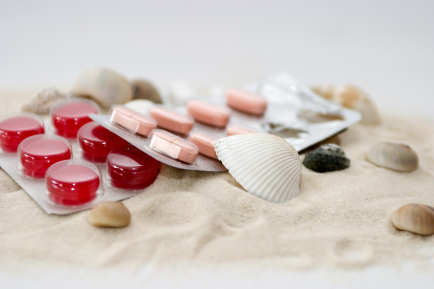 Tabletten gegen Seekrankheit liegen auf Sand